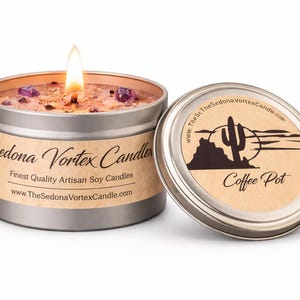 Può includere: Una candela accesa in un barattolo argentato con la scritta "Sedona Vortex Candles" e un coperchio con la scritta "Coffee Pot". La candela ha un'etichetta marrone e pietre viola. L'indirizzo del sito web è visibile.