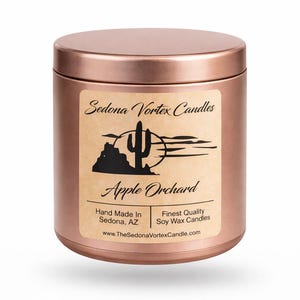 Può includere: Un barattolo di candela color rame con un'etichetta raffigurante un paesaggio desertico e il testo "Sedona Vortex Candles" e "Apple Orchard". L'etichetta indica anche "Hand Made In Sedona, AZ."