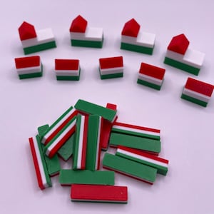 May include: A collection of red, white, and green miniature houses and rectangular blocks. The houses have a white roof and a red base with a green stripe. The blocks have a red, white, and green stripe pattern.