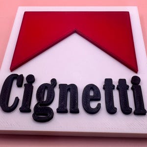 May include: A white square sign with a red chevron shape at the top and the word "Cigarette" in black lettering.