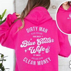 Puede incluir: Sudadera con capucha rosa con un gr&aacute;fico blanco que dice "Dirty Man - Blue Collar - Rare Breed - Blue Collar Wife - Est. MMXIV - Dollar Club - Clean Money".