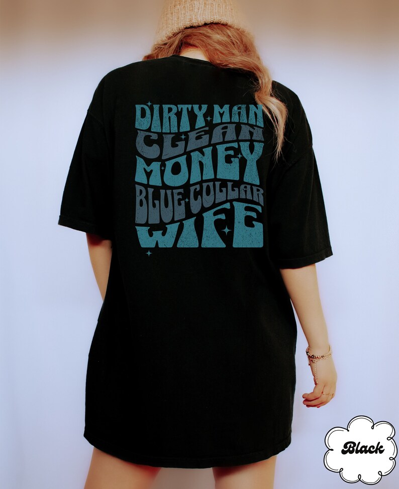 Może przedstawiać: Czarny T-shirt z niebieskim nadrukiem, na kt&oacute;rym widnieje napis "Dirty Man Clean Money Blue Collar Wife" w retro stylu.