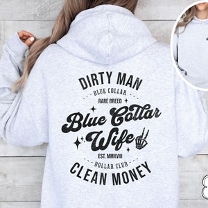 Puede incluir: Sudadera con capucha gris ceniza con un estampado gr&aacute;fico negro que dice "Dirty Man Blue Collar Rare Breed Blue Collar Wife Est. MMXVIII Dollar Club Clean Money".