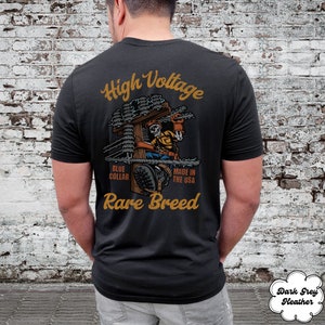 May include: Black t-shirt with a graphic of a skeleton electrician working on a power pole. The text "High Voltage", "Blue Collar", "Made in the USA", and "Rare Breed" is printed on the shirt.
