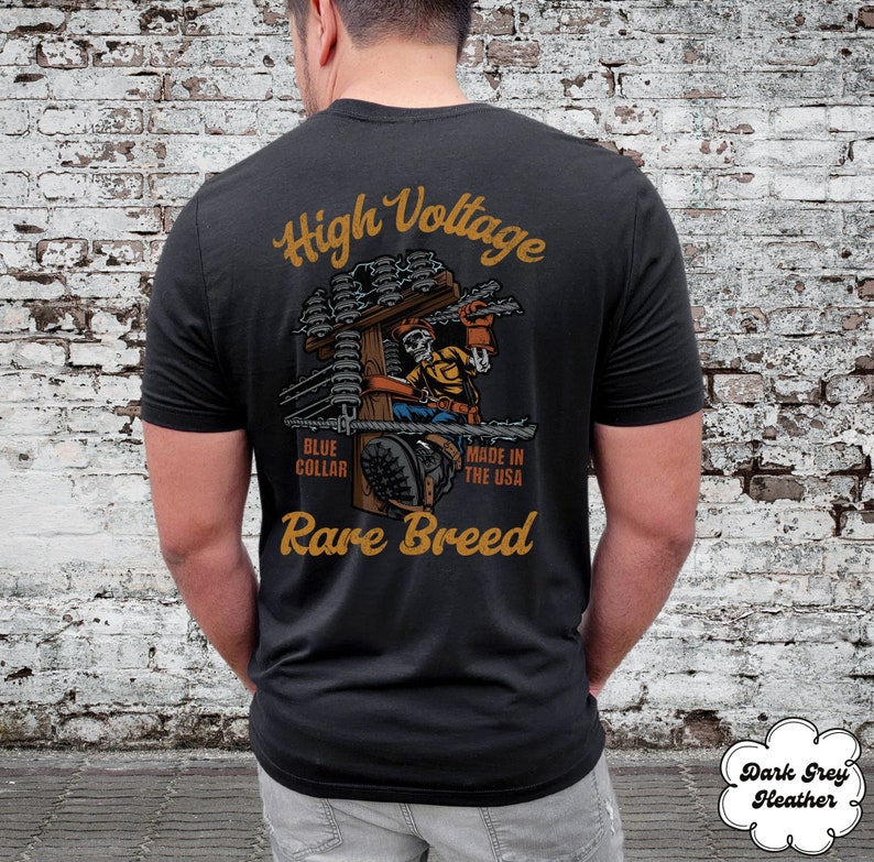 May include: Black t-shirt with a graphic of a skeleton electrician working on a power pole. The text "High Voltage", "Blue Collar", "Made in the USA", and "Rare Breed" is printed on the shirt.
