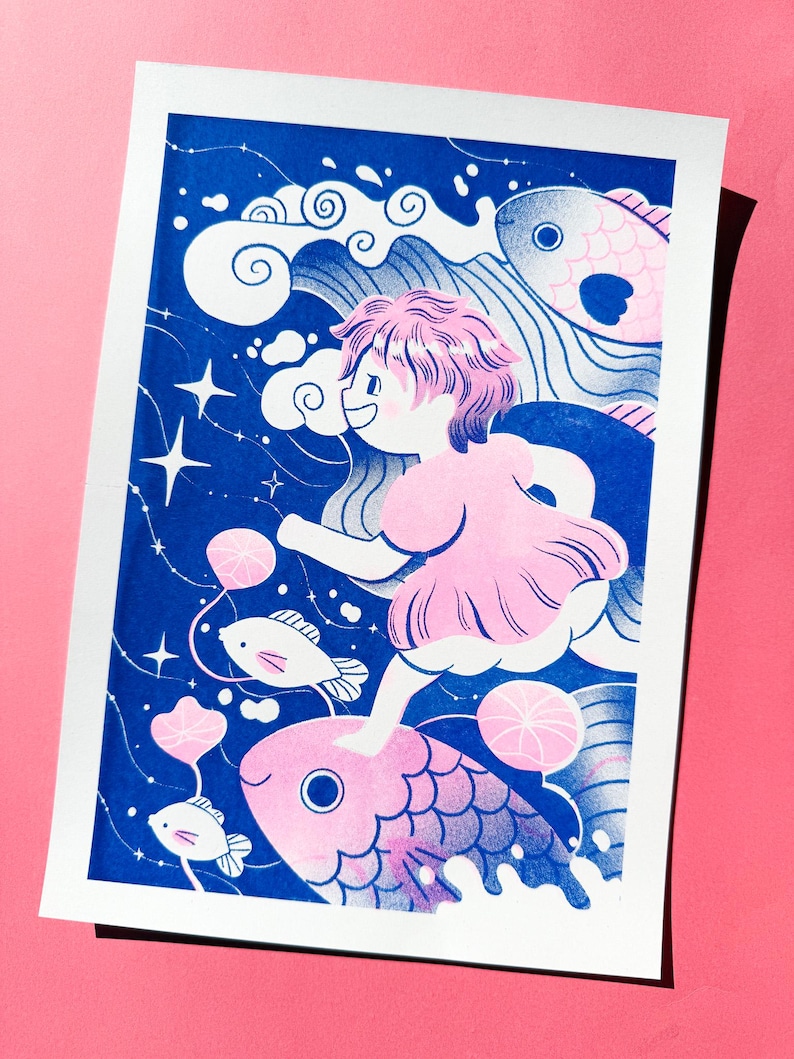May include: A whimsical art print featuring a young person with pink hair and a pink dress, riding a large pink fish through a blue ocean. The illustration includes white clouds, stars, and smaller fish, creating a dreamlike scene.