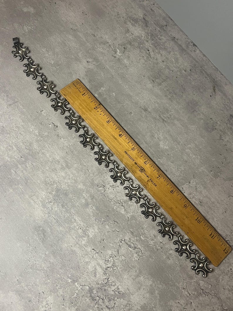 Peut inclure: Un bracelet en argent avec un motif g&eacute;om&eacute;trique r&eacute;p&eacute;titif. Le bracelet mesure environ 18 cm de long.