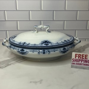 May include: A white porcelain serving dish with a blue and white floral pattern. The dish has a lid with a decorative handle.