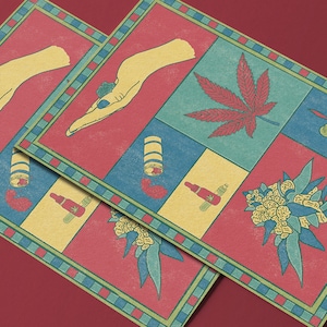 May include: Two square art prints with a red, blue, and yellow color scheme. Each print features a hand, cannabis leaf, lighter, and other related illustrations. The prints have a decorative border and are displayed on a red surface.