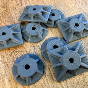 May include: Eight gray plastic square and round shaped pieces with a center hole and a starburst design around the hole.