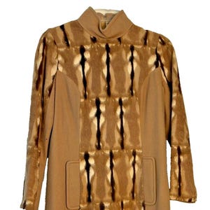 May include: A tan vintage coat with a high collar and long sleeves. The coat has a distinctive pattern of vertical brown and black stripes on the front and sleeves, with two front pockets.
