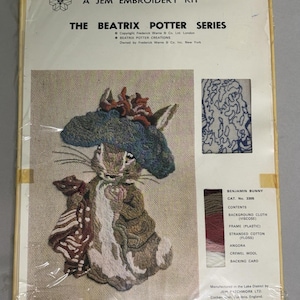 May include: A Jem Embroidery Kit from The Beatrix Potter Series featuring Benjamin Bunny. The package includes a printed background cloth, a blue hat, brown coat, and various colored threads. Text includes copyright information and contents list.