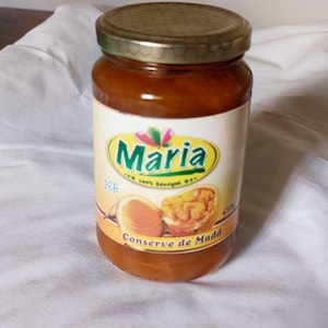 Puede incluir: Un tarro de cristal de conserva de Madd de la marca Maria. El tarro tiene una tapa dorada y una etiqueta con el nombre de la marca y un gráfico de la fruta. La conserva es de color marrón-naranja y el tarro es de 450g.
