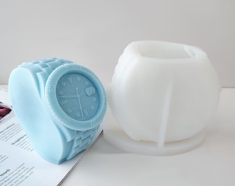 May include: A light blue silicone mould of a wristwatch with a white silicone mould of the same watch.