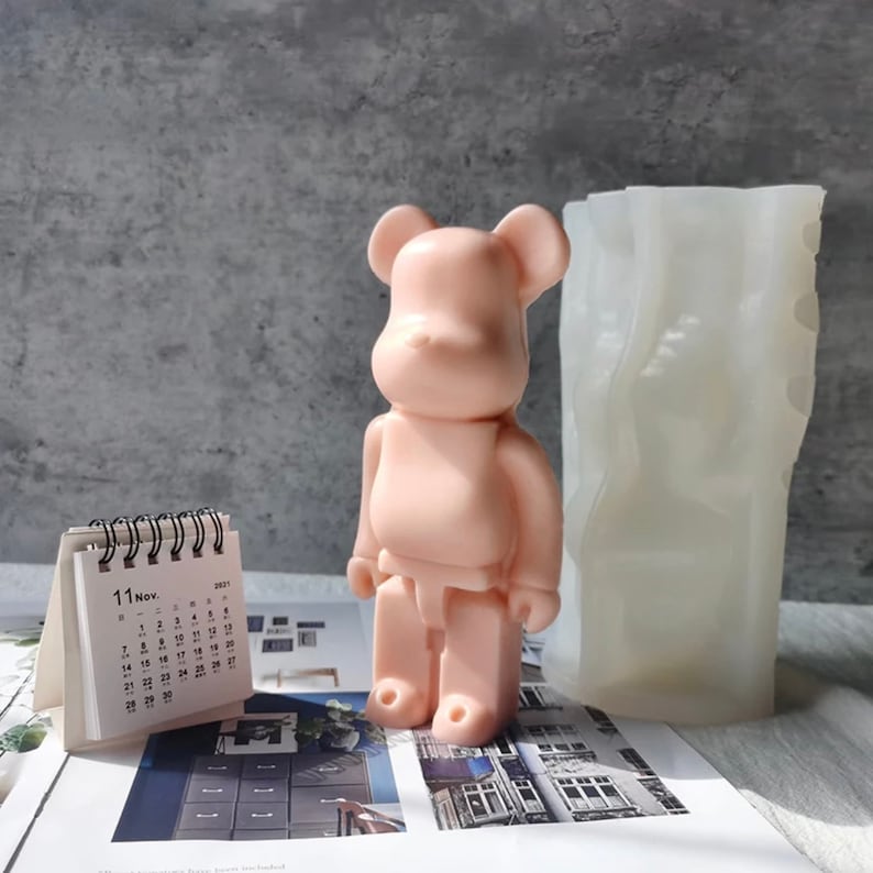 May include: A pink bear-shaped silicone mold for making candles or soap. The mold is next to a calendar with the date "11 Nov. 2021" on it.