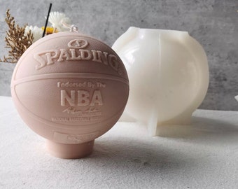May include: A pink basketball candle with the Spalding logo and "Endorsed By The NBA" text. The candle is next to a white silicone mold.