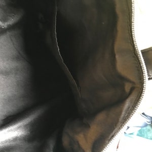 May include: The inside of a black bag with a zipper. The lining is a smooth, black fabric.