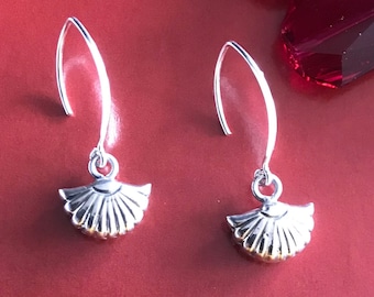 May include: A pair of silver dangle earrings featuring a seashell design. The earrings have a simple hook fastening.