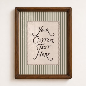 Op de afbeelding: Een rechthoekige houten lijst met een crèmekleurig centraal paneel met de tekst Your Custom Text Here in donkerbruin schrift. De achtergrond achter het centrale paneel heeft een patroon van verticale saliegroene en crèmekleurige strepen.