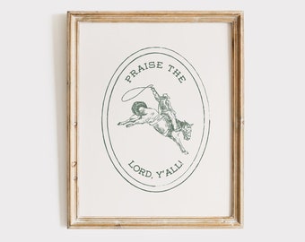 May include: A framed print with a green illustration of a cowboy riding a horse and lassoing. The text around the illustration reads "Praise the Lord, Y'all".