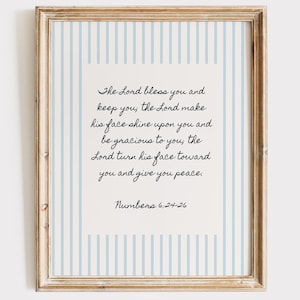 May include: A framed print with a light blue and white striped background. The print features a cream-coloured rectangle with elegant script that reads "The Lord bless you and keep you...Numbers 6:24-26."