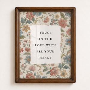 May include: A rectangular wooden frame containing a print with a floral pattern in shades of pink, blue, and yellow. Centered on the floral background is a white rectangular area with the black text: TRUST IN THE LORD WITH ALL YOUR HEART.
