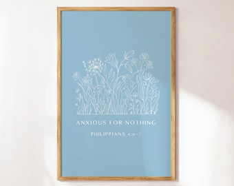 May include: A framed art print featuring a light blue background with white floral line art. The text "ANXIOUS FOR NOTHING" and "PHILIPPIANS 4:6-7" are displayed in a clean, sans-serif font. The frame is made of light brown wood.