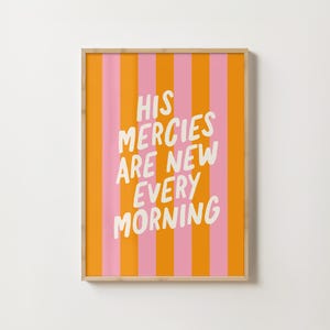 May include: A framed print with a pink and orange striped background. The text "HIS MERCIES ARE NEW EVERY MORNING" is written in white on the print.