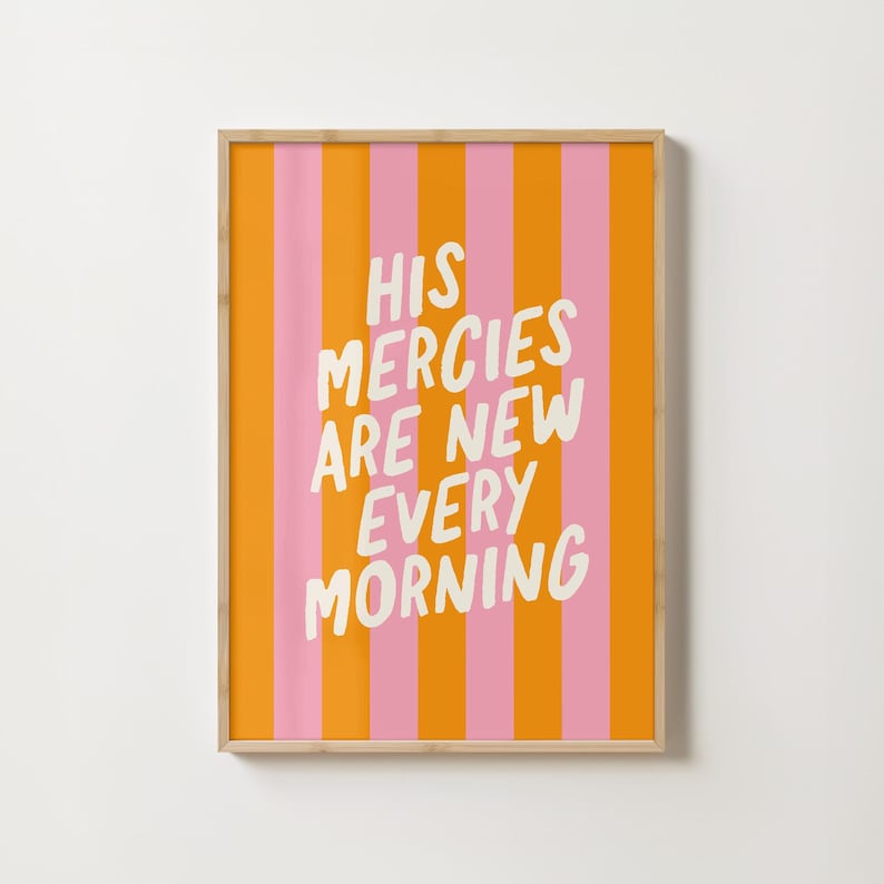 May include: A framed print with a pink and orange striped background. The text "HIS MERCIES ARE NEW EVERY MORNING" is written in white on the print.