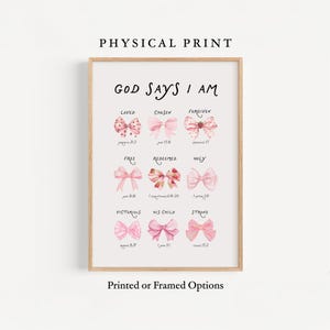 Pode incluir: Uma impressão emoldurada com o texto "GOD SAYS I AM" e várias afirmações como "AMADO" e "ESCOLHIDO", cada uma acompanhada por uma ilustração de laço. A impressão está em uma moldura de madeira e inclui o texto "Printed or Framed Options".