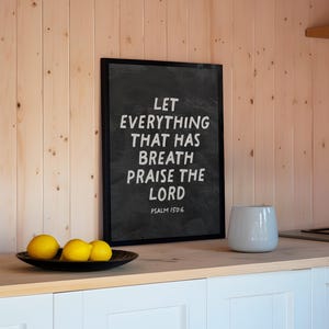 Può includere: Lavagna nera incorniciata con testo bianco: «LET EVERYTHING THAT HAS BREATH PRAISE THE LORD» e «PSALM 150:6». Sono visibili anche una ciotola di legno con limoni e un vaso di ceramica bianco.