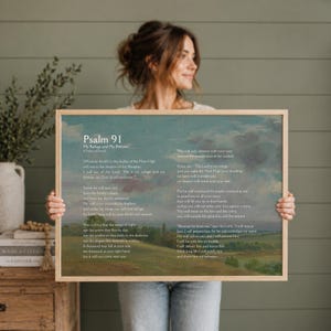 May include: A framed print of Psalm 91, with text in a classic font. The artwork has a landscape background with a soft, painterly style. The frame is a light wood colour, and the overall aesthetic is serene.