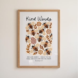 Puede incluir: Una lámina enmarcada con el texto Kind Words are like honey - sweet to the soul and healthy for the body. Proverbs 16:24. El diseño incluye ilustraciones de abejas marrones y beige, panales y hojas sobre un fondo de color crema.