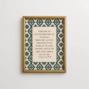 Puede incluir: Una impresión enmarcada con un marco dorado. La impresión presenta un fondo color crema con texto de 1 Corintios 15:58. El borde tiene un patrón repetitivo de diseños florales azul oscuro y verde.