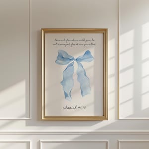 May include: A framed print featuring a watercolor illustration of a light blue bow. The artwork includes the text "Fear not, for I am with you, be not dismayed, for I am your God. Isaiah 41:10" in black script. The frame is gold.