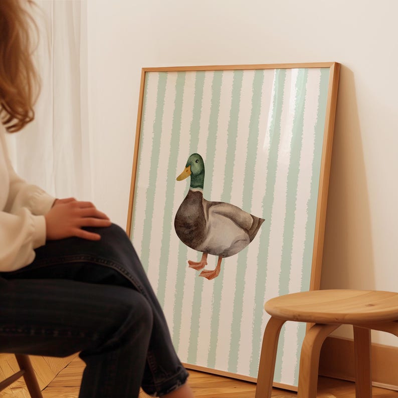 Op de afbeelding: Een aquarel van een wilde eend op een lichtgroen-wit gestreepte achtergrond. De eend kijkt naar links en heeft een groene kop, een bruin lichaam en grijze vleugels.