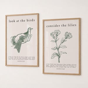 以下が含まれることがあります： 鳥と植物のイラストが描かれた2つの額入りアートプリント。1つは鳥を手に持った手と「look at the birds」の文字が特徴です。もう1つは花の模様と「consider the lilies」の文字が特徴です。どちらも薄いベージュ色の背景です。