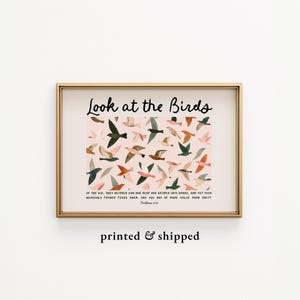 May include: A framed art print with a gold-coloured frame. The artwork depicts a pink background with various birds in flight, in shades of green, brown, and pink. The text "Look at the Birds" is at the top, with a Bible verse below.