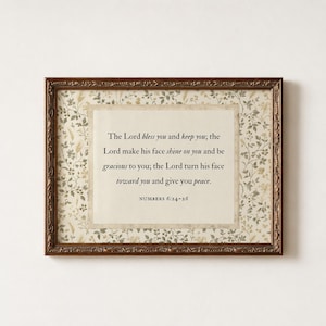 May include: A rectangular wall art piece in an ornate dark bronze frame. The center features a cream-colored paper with the text: The Lord bless you and keep you; the Lord make his face shine on you and be gracious to you; the Lord turn his face toward you and give you peace. NUMBERS 6:24-26. The background has a botanical pattern.