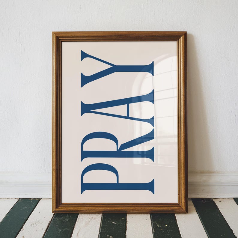May include: A framed print with a white background and the word "PRAY" in large, bold, blue letters.