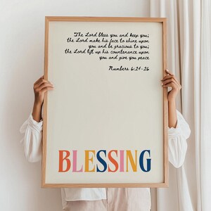 May include: A framed print with a white background and black text. The text reads "The Lord bless you and keep you; the Lord make his face to shine upon you and be gracious to you; the Lord lift up his countenance upon you and give you peace Numbers 6:24-26". The word "BLESSING" is written in large, colorful letters at the bottom of the print.