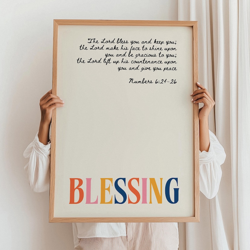 May include: A framed print with a white background and black text. The text reads "The Lord bless you and keep you; the Lord make his face to shine upon you and be gracious to you; the Lord lift up his countenance upon you and give you peace Numbers 6:24-26". The word "BLESSING" is written in large, colorful letters at the bottom of the print.
