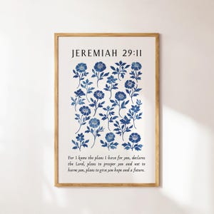 May include: A framed print with a floral pattern in blue hues. The print displays the text "JEREMIAH 29:11" and a Bible verse. The artwork is presented in a wooden frame, suitable for home decor.