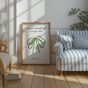 May include: A framed print with a green bow illustration and the text "every good and perfect gift comes from above James 1:17". The print is hanging on a white wall above a blue and white striped couch.