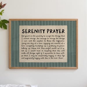 Könnte beinhalten: Gerahmter Druck des Serenity Prayer. Der Text befindet sich auf einem beigen Stoff, vor einem grün gestreiften Hintergrund und in einem Holzrahmen. Das Gebet ist in schwarzer Schrift geschrieben.