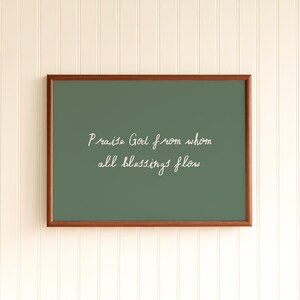 May include: A framed rectangular sign with a dark green background and a brown wooden frame. The white cursive text reads "Praise God from whom all blessings flow."