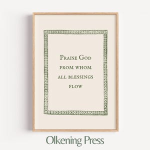 May include: A framed print with the text "Praise God from Whom All Blessings Flow." The print has a cream-colored background with a decorative green border. The frame is made of light-colored wood. The text "Olkening Press" is at the bottom.