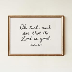 Puede incluir: Impresión enmarcada con el texto "Oh taste and see that the Lord is good -Psalm 34:8" en escritura negra. El marco rectangular dorado rodea un fondo blanco. Ideal para la decoración del hogar.