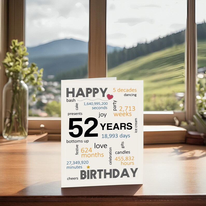 Celebrate a 52nd birthday with an enchanting card on a table, set against a beautiful landscape backdrop. The birthday card features joyful wishes like cheers, joy, gifts, love, and a special mention of the exact years, months, days and hours.