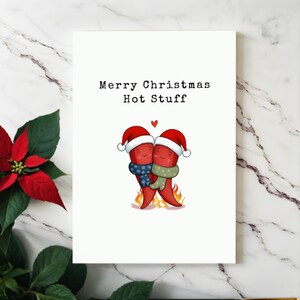 This card features two adorable hot peppers hugging in love, complete with a flame underneath and Santa hats for a holiday touch. The message Merry Christmas Hot Stuff adds a spicy, romantic vibe, making it perfect for your partner this Christmas.